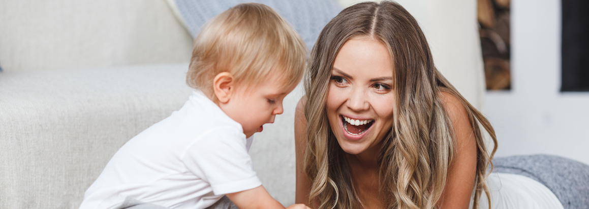 cute blonde mother and child boy play together indoors at home on the carpet