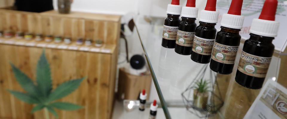 epa07972000 Small bottles (R) containing CBD (Cannabidiol) oil are on display at the ‘Flowers Shop CBD’, of its creator Anthony Mamone (L, background), in Cannes, southern France, 04 November 2019. The French National Assembly in October voted in favor of experimenting with therapeutic cannabis, starting in the first quarter of 2020.  EPA/SEBASTIEN NOGIER