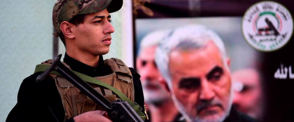 epa08110527 A member of Iran-backed Iraqi Shiite armed group popular mobilization forces stands guard next to placard carrying an obituary notice and the pictures of slain Abu Mahdi al-Muhandis and the Iranian general Qasem Soleimani in front of a military base in Baghdad, Iraq, 07 January 2020.  A US drone strike killed Iraqi militia commander Abu Mahdi al-Muhandis and Qasem Soleimani, the head of Iran’s Islamic Revolutionary Guard Corps’ elite Quds Force, and the eight others at the Baghdad international airport on 03 January 2020.  EPA/MURTAJA LATEEF