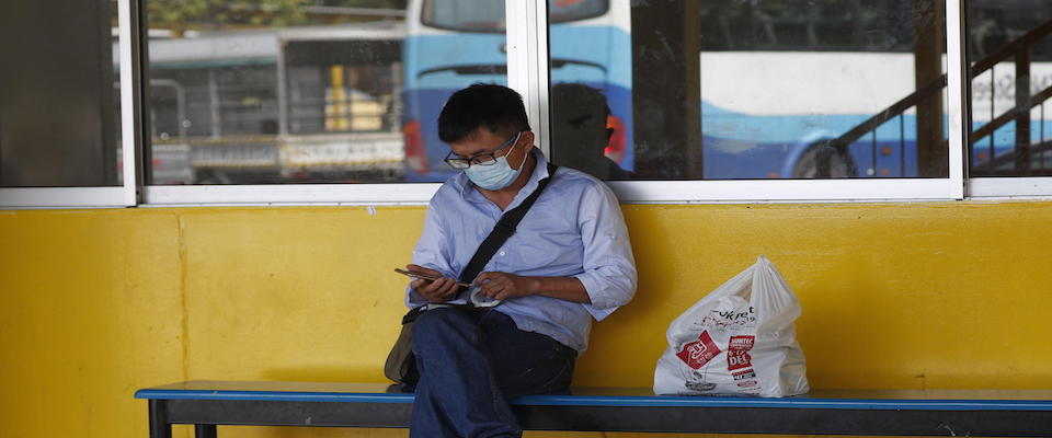 epa08197055 A man wearing a surgical mask uses a mobile phone at the Tuas View dormitory in Singapore, 06 February 2020. Singapore’s Ministry of Health has confirmed that 28 patients, including a six-month-old infant, have tested positive for the novel coronavirus (2019-nCoV). Four of those cases were found to have been passed through local transmission at a Chinese health product store.  South Korea and Malaysia health authorities have also reported patients who caught the virus while visiting Singapore last month.  EPA/WALLACE WOON