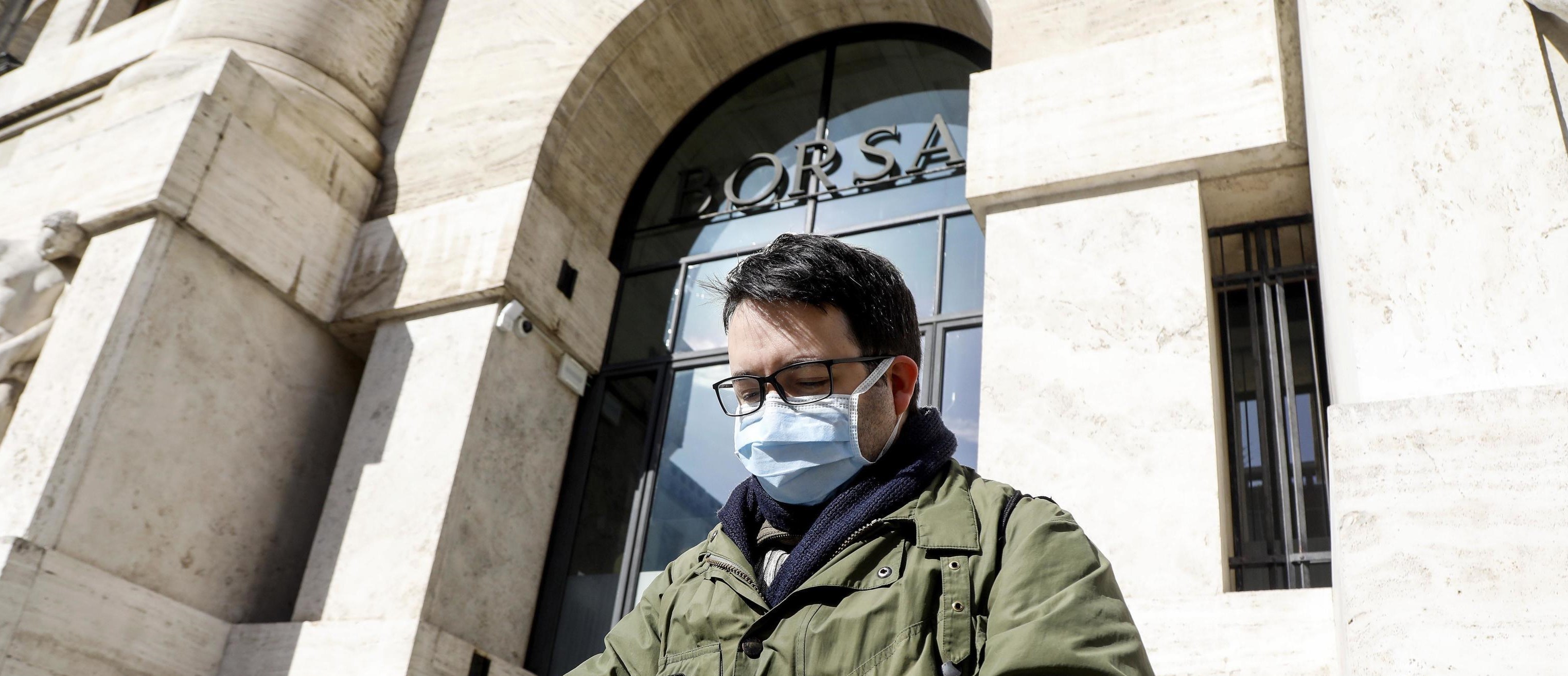 Persone con mascherine per proteggersi dal Coronavirus in piazza affari davanti all’ingresso della Borsa a Milano, 24 gennaio 2020.ANSA/Mourad Balti Touati