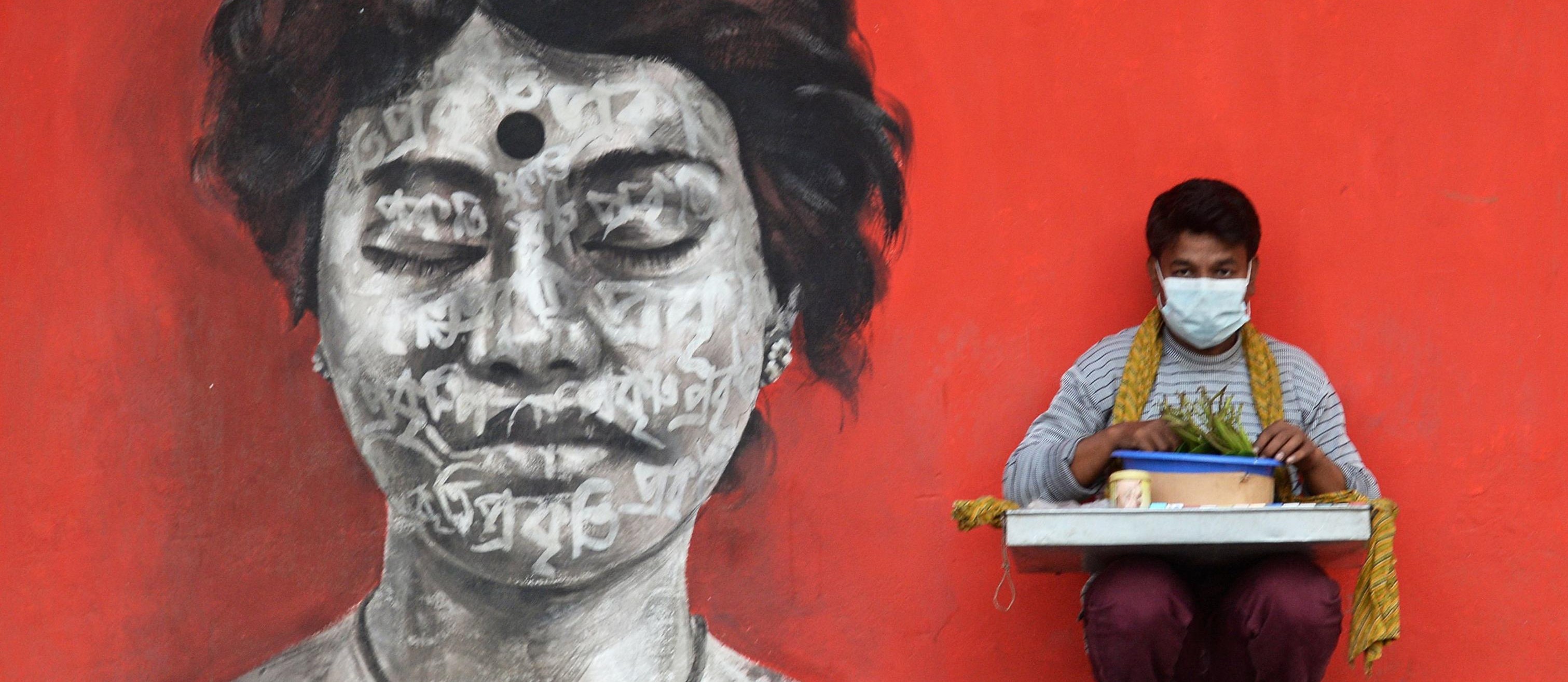 A street vendor wearing a facemask amid concerns of the spread of the COVID-19 coronavirus sells cigarettes on a street, in Dhaka on March 12, 2020. (Photo by Munir Uz zaman / AFP)