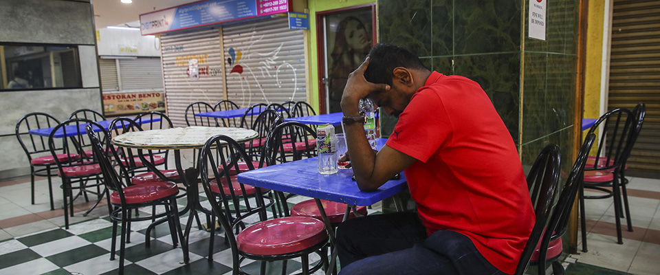 epa08302953 A restaurant owner sits at a table during the first day of a movement control order issued by the Malaysia government, Malaysia, 18 March 2020. The Malaysian government announced a two week nation-wide  ‘Movement Control Order’ to contain the spread of Covid -19 coronavirus infection in Malaysia.  EPA/FAZRY ISMAIL