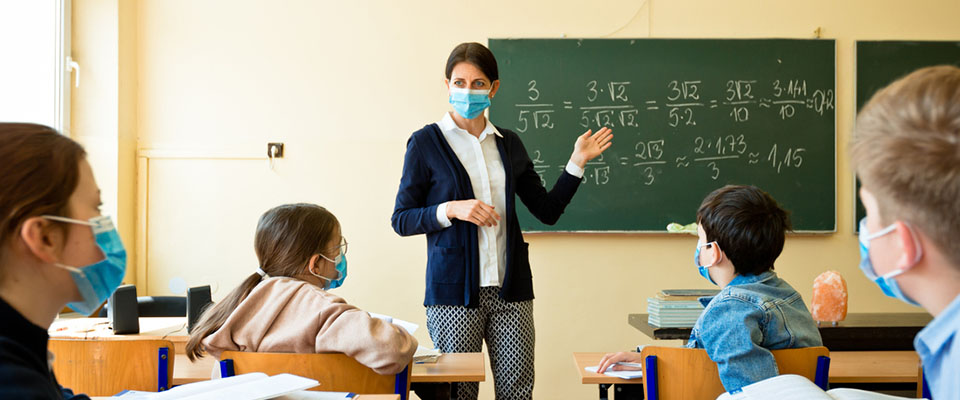 A teacher wearing a N95 Face masks teaches mathematics at an High School