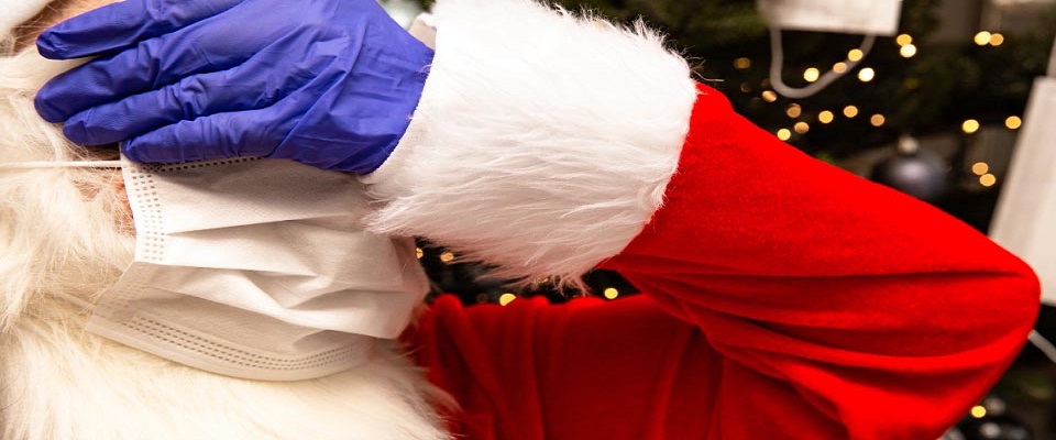 Santa Claus wearing a Face Mask and protective safety gloves for Covid-19, Santa standing by the Christmas tree unhappy about Coronavirus. close-up